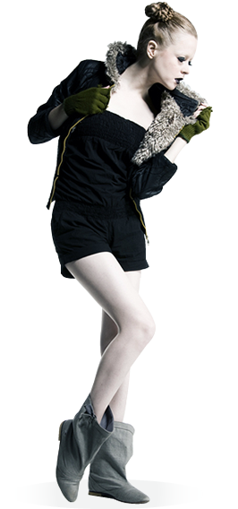 A pale-skin female model with dark eye shadow and tied up hair wears dark green gloves, gray linen boots, and a woolen lined hood on a black zip-up jacket over a black top and shorts. She holds her jacket open with both hands and slightly raises her left knee whilst looking to the floor
